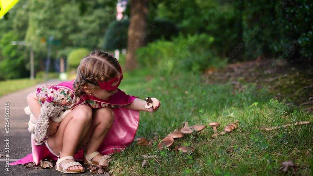 cute baby girl in superhero costume exploring the mushrooms on her walk through the town cute baby girl in superhero costume exploring the mushrooms on her walk through the town