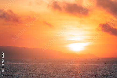 Beautiful cloudscape over the sea  sunrise shot. Lonely boats. Vung Tau beach  Vietnam with beautiful yellow sunrise sky  sun and clouds in orange and blue tones.