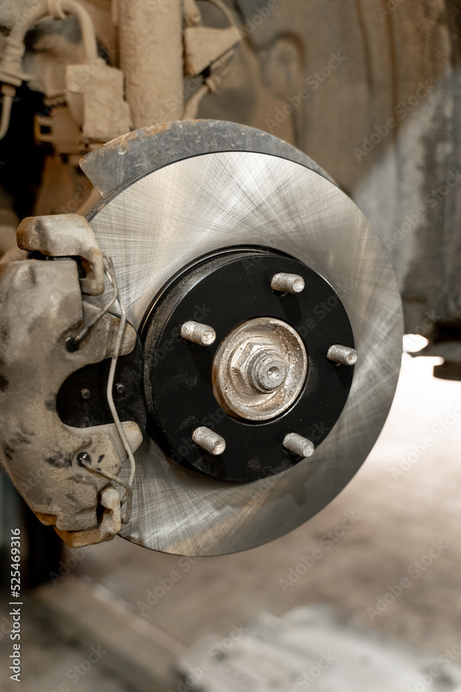 Disc brake on a car, brake disc replacement in a car service. The rim is removed, exposing the rotor and caliper.