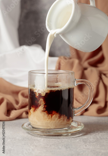 Pouring creme in a cup of coffee.