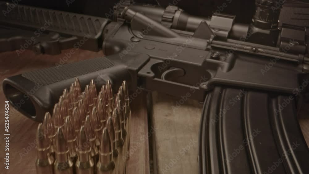 High angle dolly out from loaded AR-15 assault rifle with a small amount of ammunition in the foreground