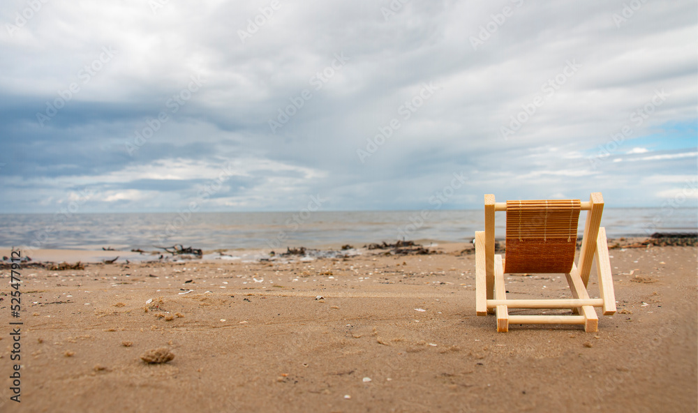a luxurious deck chair on the shore by the sea to relax and enjoy the view of the summer seascape with thunderclouds