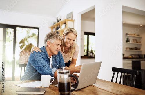 Couple with laptop planning finance, banking and checking retirement budget while becoming debt free at home. Smiling, happy and cheerful mature man showing woman an approved bank loan on technology photo