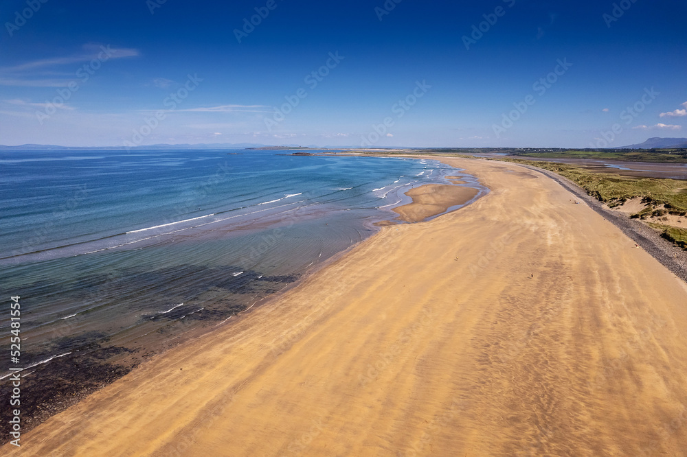 Aerial view on Streedagh beach in county Sligo, Ireland. Beautiful nature scene with warm yellow sand and blue ocean and clear blue sky. Popular tourist area. Warm sunny day. Aerial view on Streedagh beach in county Sligo, Ireland. Beautiful nature scene with warm yellow sand and blue ocean and clear blue sky. Popular tourist area. Warm sunny day.