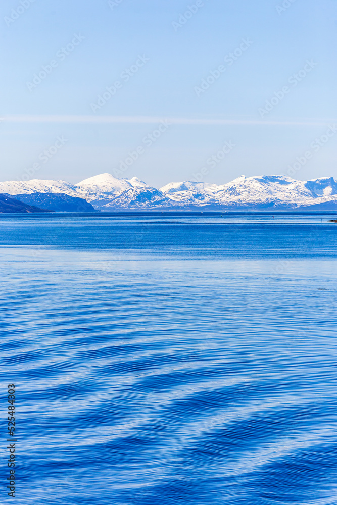 Seascape view with wave pattern and a snow capped mountain range Seascape view with wave pattern and a snow capped mountain range