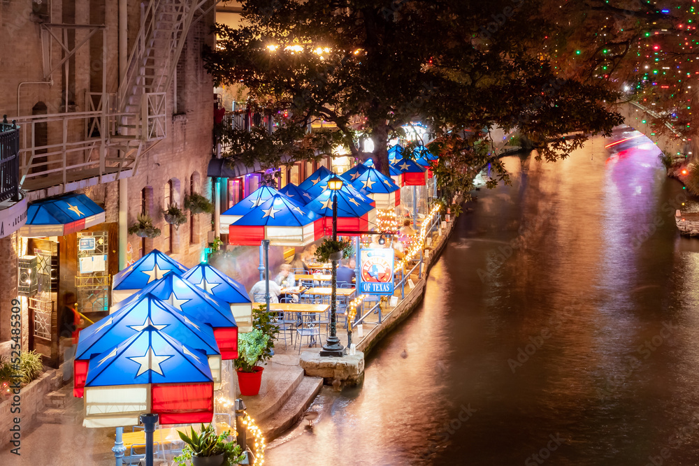 Texas flag umbrellas and Christmas lights at the restaurants at the San Antonio Riverwalk on a December Texas evening