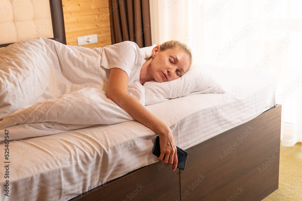 Woman phone beautiful sleep mobile blonde bed blanket eyes lying, from adult relax in dream and smile bedding, room healthy. Face cozy relaxing, lie