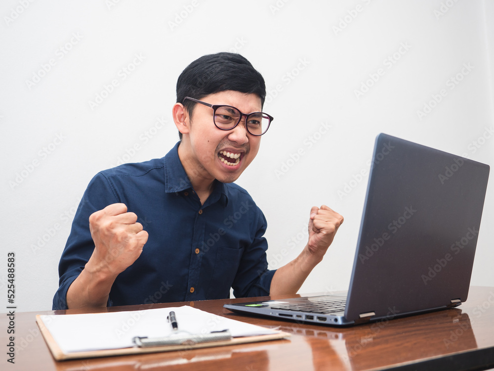 Male employee show fist up feels happy about successful with working on table Male employee show fist up feels happy about successful with working on table