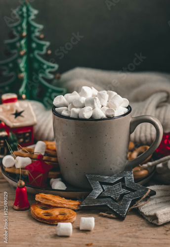 Coffee or cocoa with marshmallows in a ceramic mug, wooden Christmas toys and decorations, sweets on a dark background. Cozy composition with Christmas decor
