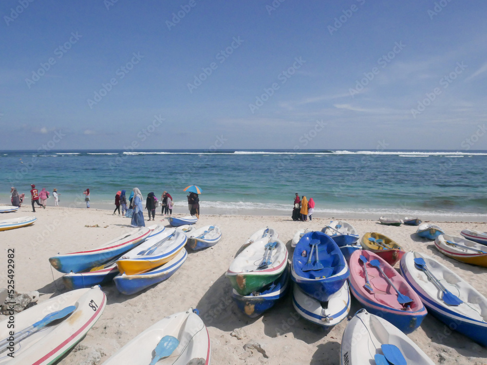 Bali, Indonesia - February 28, 2019 : Tourists playing on the beach with rows of colorful boats Bali, Indonesia - February 28, 2019 : Tourists playing on the beach with rows of colorful boats