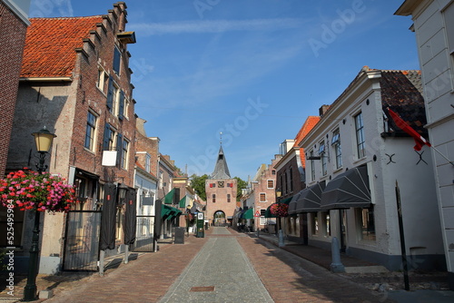Traditional historic medieval houses in the old picturesque fortified town of Elburg, Gelderland, Netherlands, with the well preserved old city gate Vischpoort in the background