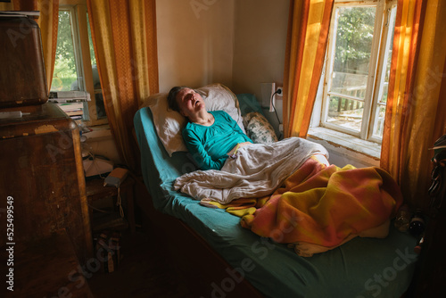 Paralyzed elderly lady lying on bed at home photo