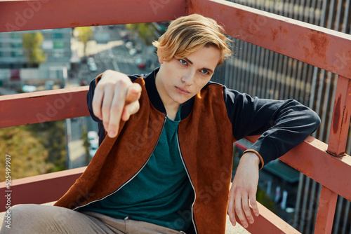 Young blond male sitting on roof of building