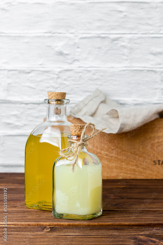 Lemon and lime syrups in glass bottles on wooden table.