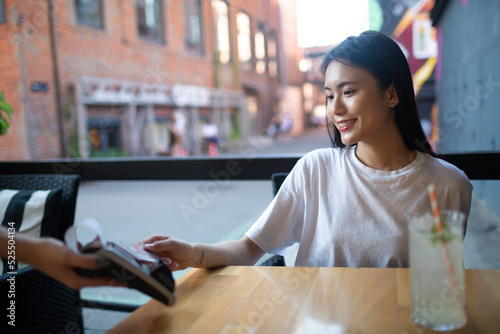 Fotografia Asian Woman pay with credit card contactless payment terminal cashier in outdoor cafe