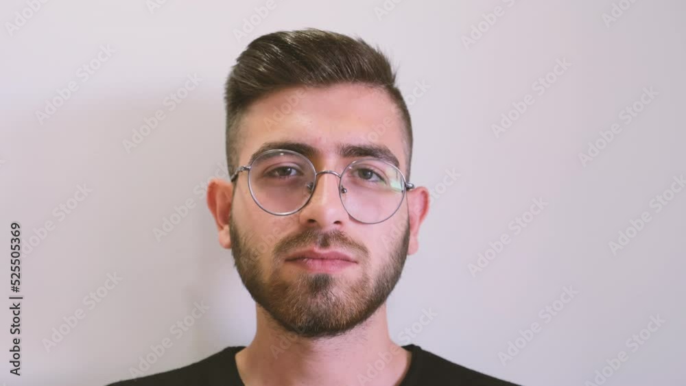 Looking camera, close up front view portrait of young man looking camera. Isolated on white background. Facial expression concept footage idea. Caucasian male wearing glasses.