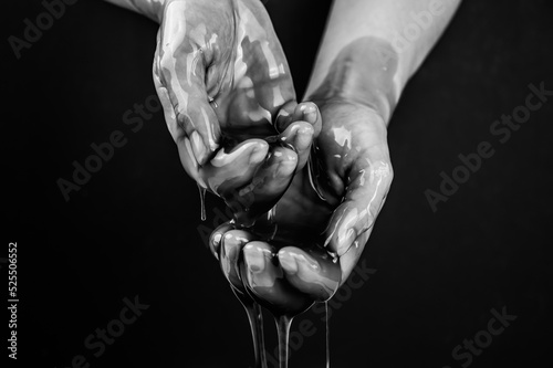Women's hands in a viscous liquid similar to blood. Black and white photo. photo