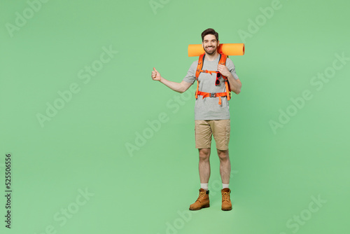 Full body young happy traveler white man carry backpack stuff mat walk do hitch-hiking gesture isolated on plain green background. Tourist leads active lifestyle. Hiking trek rest travel trip concept. #525506556