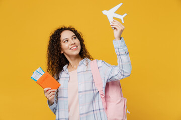 Traveler fun happy black teen girl student wear casual clothes hold passport tickets airplane isolated on plain yellow background. Tourist travel high school study abroad getaway. Air flight concept.