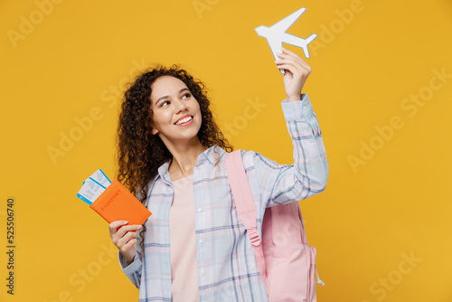 Traveler fun happy black teen girl student wear casual clothes hold passport tickets airplane isolated on plain yellow background. Tourist travel high school study abroad getaway. Air flight concept. photo