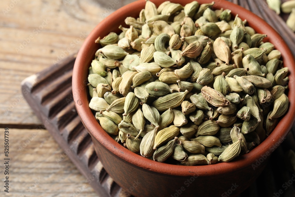 Bowl of dry cardamom pods on wooden table, closeup Bowl of dry cardamom pods on wooden table, closeup