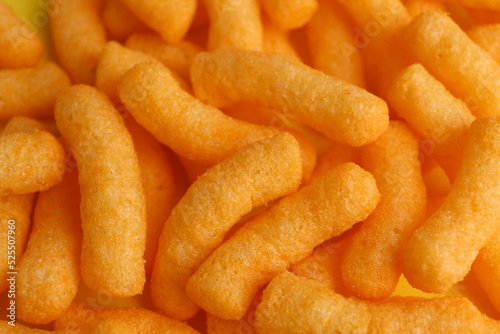 Tasty cheesy corn puffs as background, closeup