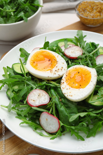 Delicious salad with boiled egg, vegetables and arugula on board, closeup