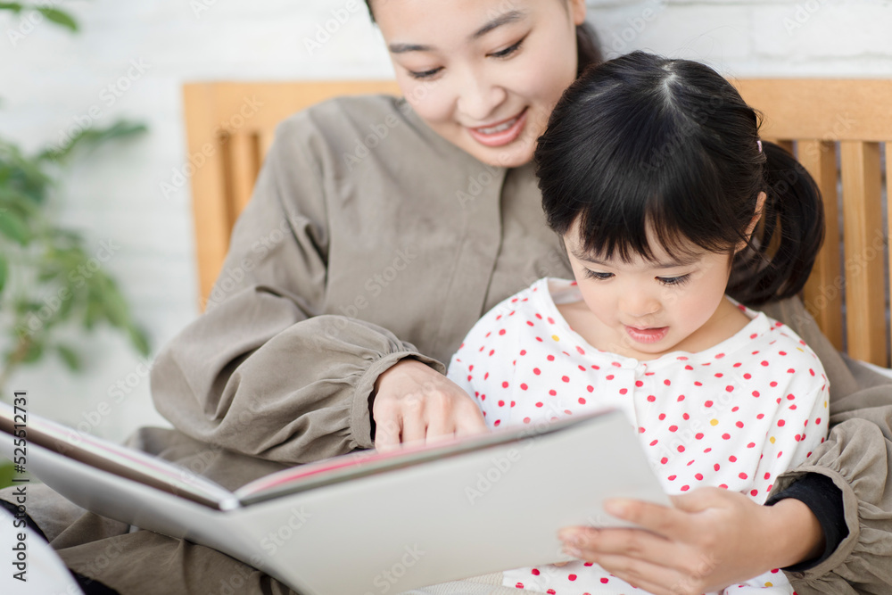 ベットで子供に本を読み聞かせする母親 ベットで子供に本を読み聞かせする母親