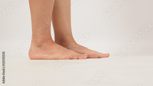 Asian woman is standing with legs and barefoot on white background. Side view