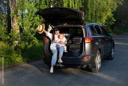 Car journey. Travel with a child by car. Mother and daughter sit in a car with an open trunk © Анна Брусницына