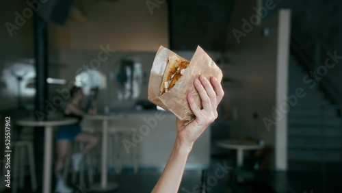 Close-up of a hand lifting a vegetarian kebab with halloumi, a mouthwatering donner kebab in front of a cafe 