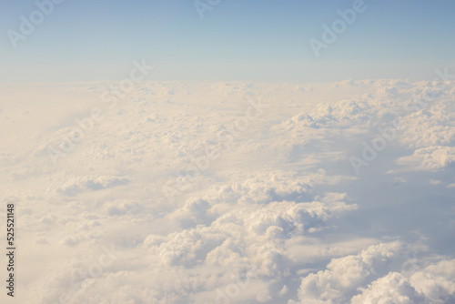 photo from airplane fluffy white beautiful clouds heaven window view.aircraft over the clouds horizon line blue sky.vacation travel concept,fly book ticket.airplane wing.sea destination