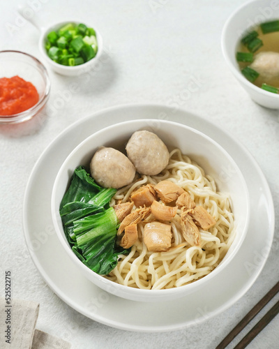 Mie ayam or bakmi ayam is a common Indonesian dish of seasoned yellow wheat noodles topped with diced chicken. Served in a white bowl.