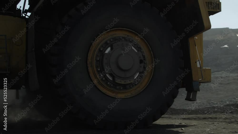 Giant mining truck drives past the camera to excavator for loading. Traffic in a coal mine Giant mining truck drives past the camera to excavator for loading. Traffic in a coal mine