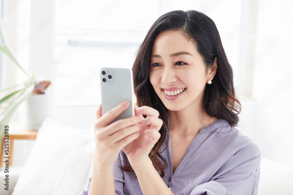 ソファに座りスマートフォンを見る女性 ソファに座りスマートフォンを見る女性