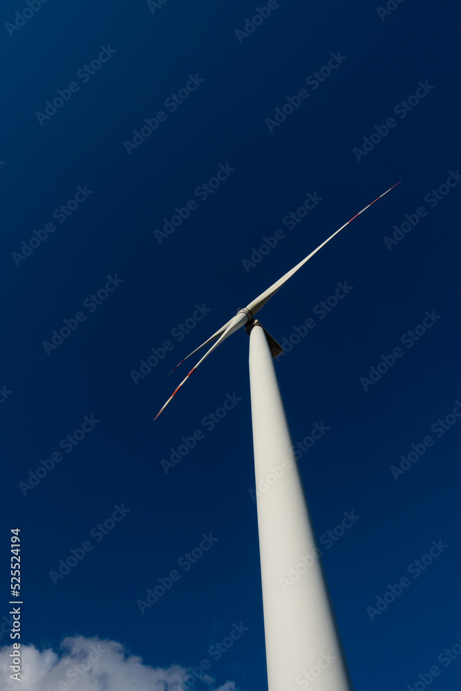 White blades of a wind turbine against the background of a navy blue sky. Renewable energy sources in the decarbonisation process. White blades of a wind turbine against the background of a navy blue sky. Renewable energy sources in the decarbonisation process.
