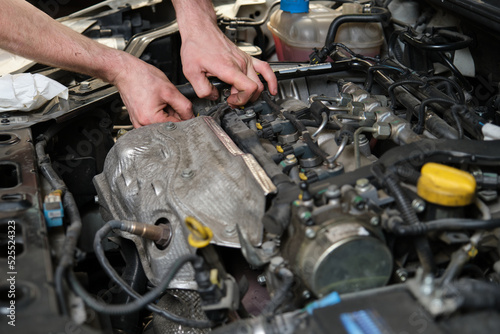 Car mechanic hands replacing a camshaft position sensor. Mechanics workshop. photo