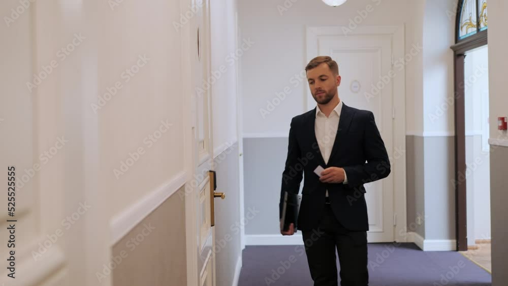 Stylish business man dressed in formal suit uses electronic key to open the door in a modern hotel. Man unlocks the door. Hotel guest using card key for opening hotel room Hotel business technologies. Stylish business man dressed in formal suit uses electronic key to open the door in a modern hotel. Man unlocks the door. Hotel guest using card key for opening hotel room Hotel business technologies.