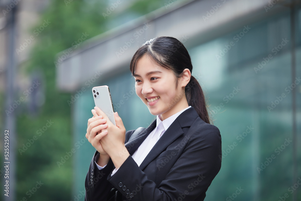 スマートフォンを持つスーツを着た笑顔の若い女性 スマートフォンを持つスーツを着た笑顔の若い女性
