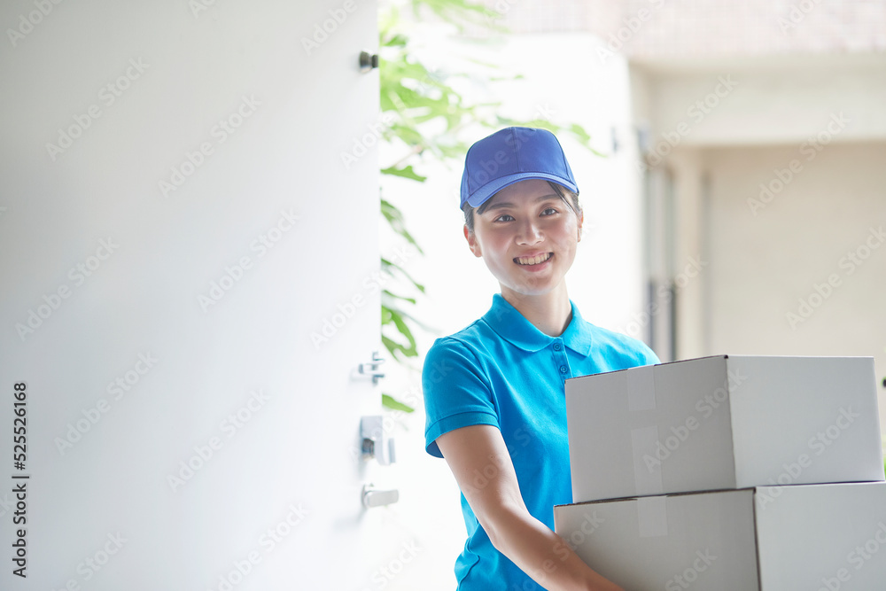 作業服を着て笑顔で荷物を運ぶ若い女性 作業服を着て笑顔で荷物を運ぶ若い女性