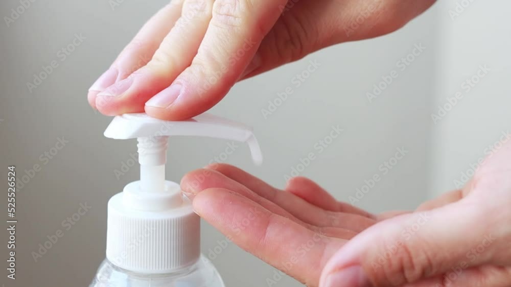 Woman hands pushing dispenser and antibacterial liquid soap squeezed out to palm, closeup on white bathroom background. Washing using soft gel for advanced skin care. Bacteria and virus protection