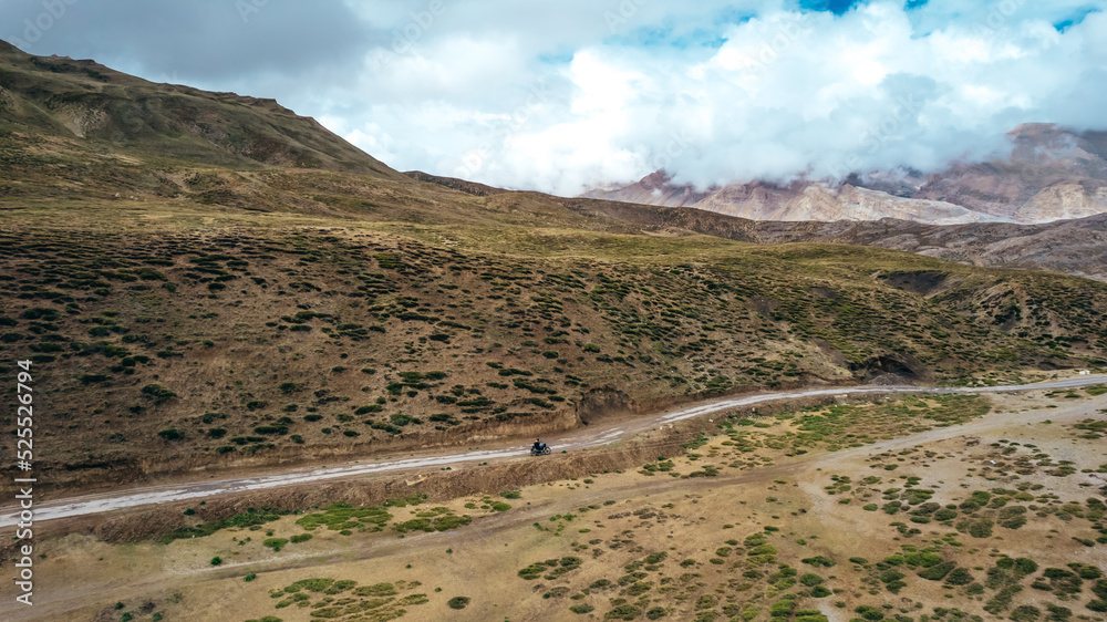 motorcycle touring Spiti Valley landscape on cloudy day through a desolate dirt road