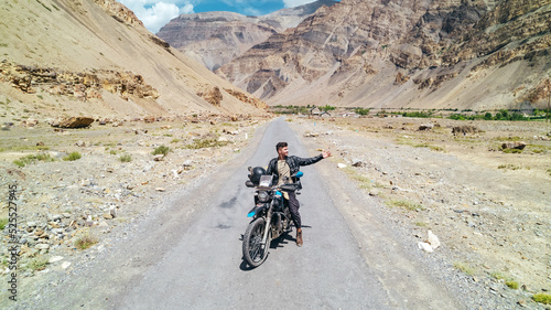 man traveling on motorcycle through Spiti Valley in Himachal Pradesh of India with extreme Himalayan Mountain landscape
