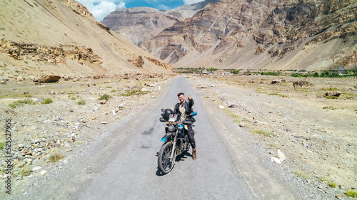 happy guy on motorcycle on desolate dry mountain road in desert of Spiti Valley Himachal Pradesh