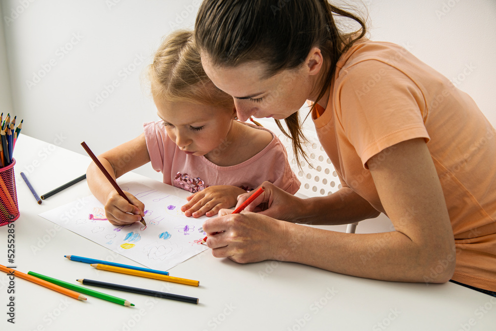 Child girl with mom draw with colored pencils on white paper Child girl with mom draw with colored pencils on white paper