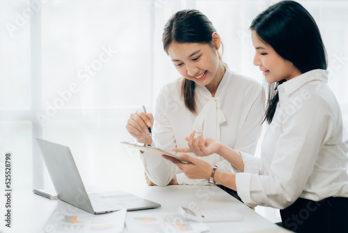 Two business Asian young women working together with laptop computer in the modern office.