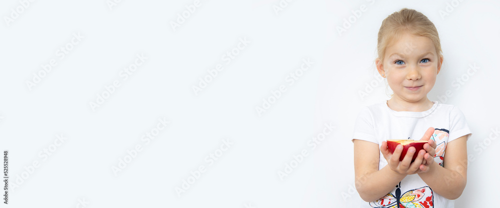 Smiling child girl blonde holding half an apple on a white background. Banner Smiling child girl blonde holding half an apple on a white background. Banner