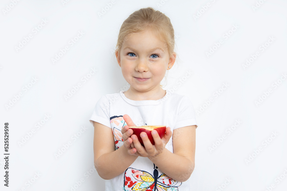 Smiling child girl blonde holding half an apple on a white background Smiling child girl blonde holding half an apple on a white background
