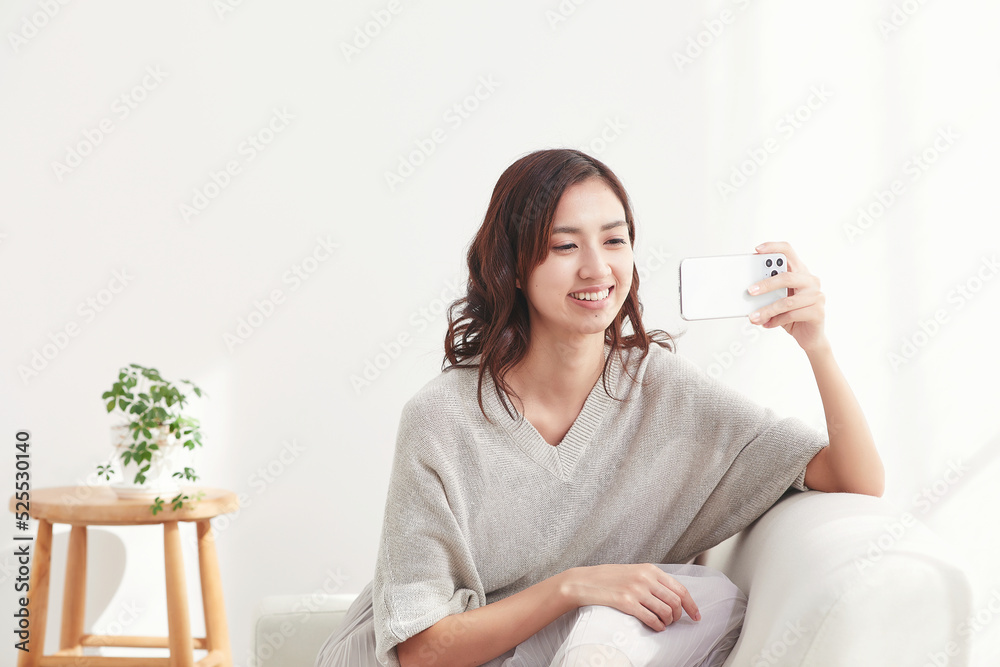 ソファに座りスマホを見る若い日本人女性 ソファに座りスマホを見る若い日本人女性
