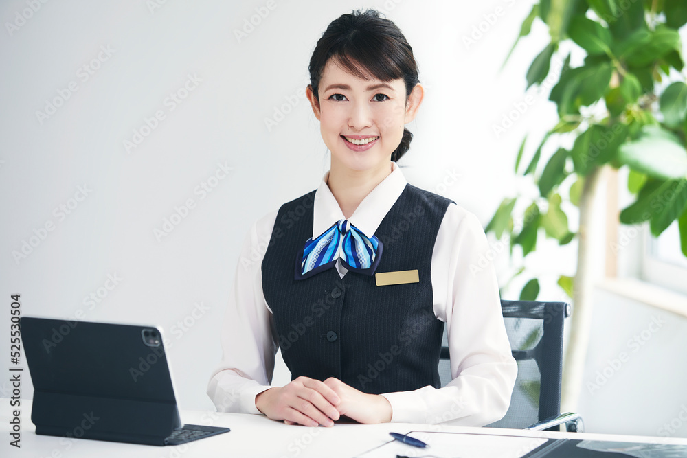 制服を着たカメラ目線の女性とタブレットPC